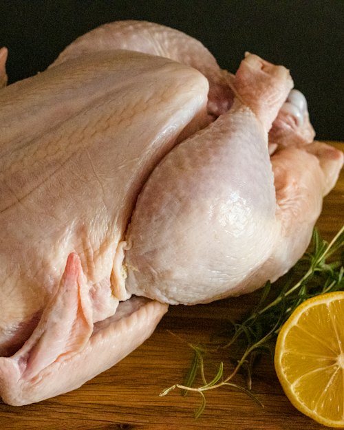 Whole raw chicken on a wooden board