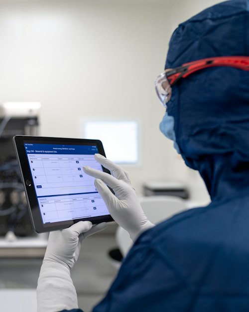 Operator in protective clothing checking production data on a tablet